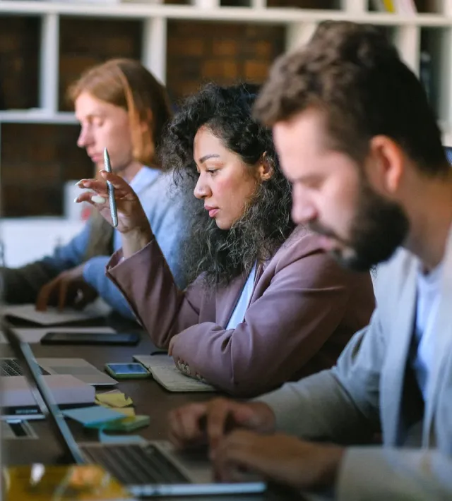 line of three people working at laptops at a desk